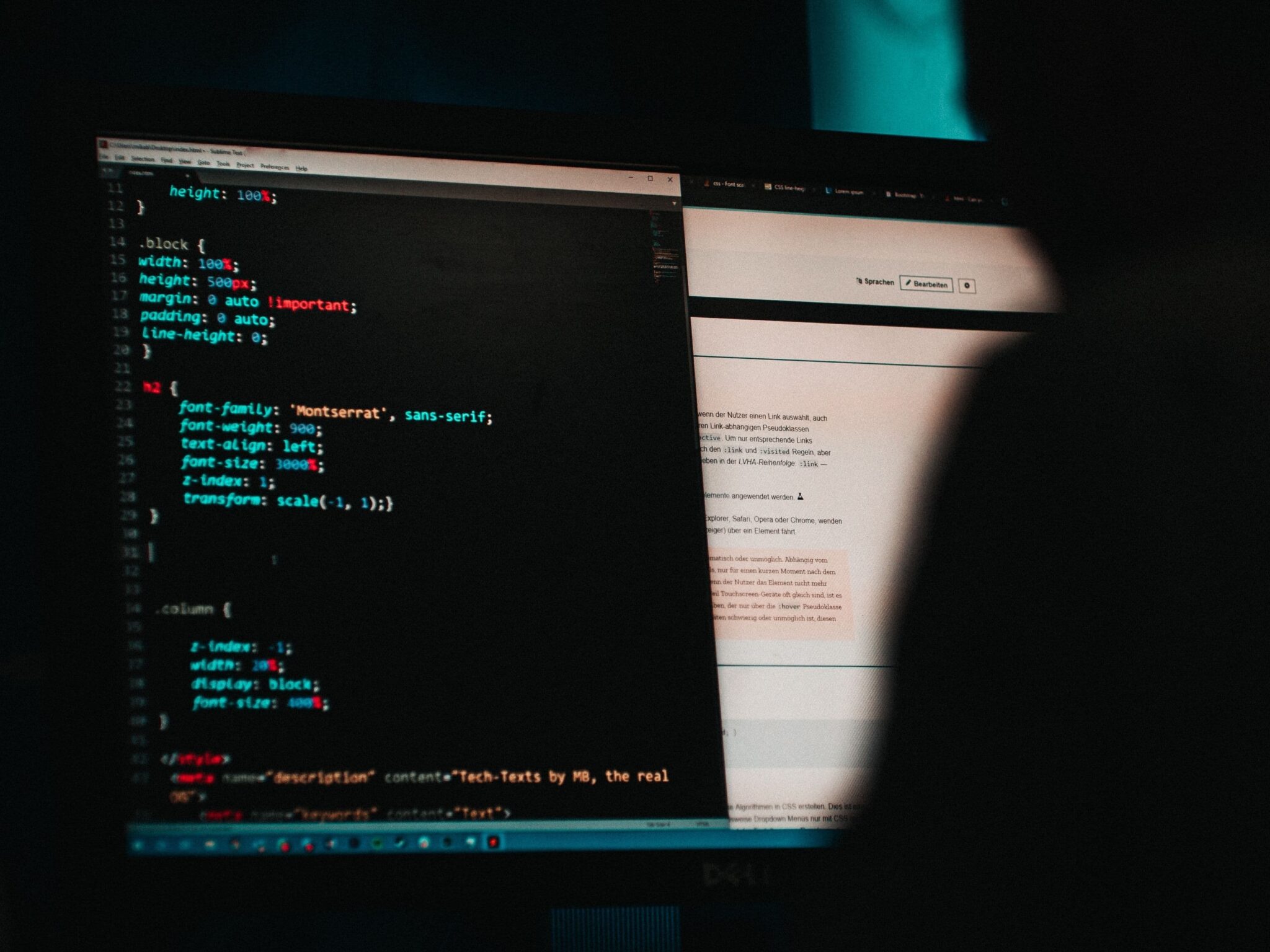 Two screens in a dark room: left monitor shows colorful code, right monitor displays a document or webpage at a brighter side.