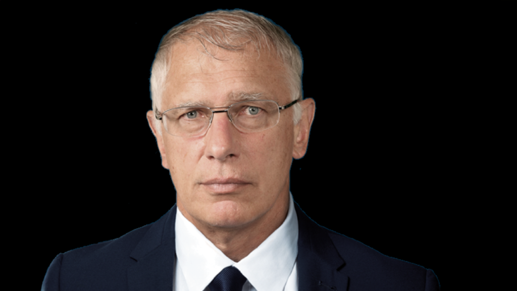 no_translation_4747_ffhaj7cer7v0iim75vzkfy4c_no_translation_translation - Crypto and Coin Professional portrait of a middle-aged man with graying hair and glasses, wearing a navy suit and white shirt against a black background, looking straight ahead.